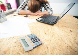 Stressed and depressed woman in home office calculating bills